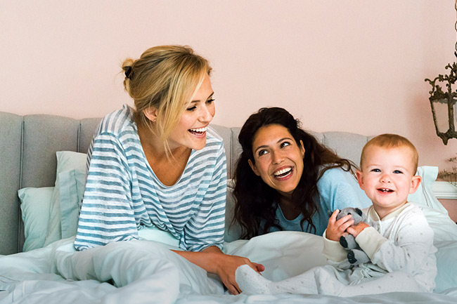 Happy mums sitting on bed after contributing to their child's Junior ISA